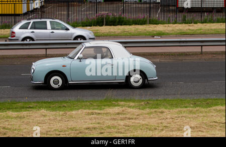 A retro 1960`s style Nissan Figaro Japanese car travelling along the Kingsway the Dual Carriageway in Dundee, UK Stock Photo